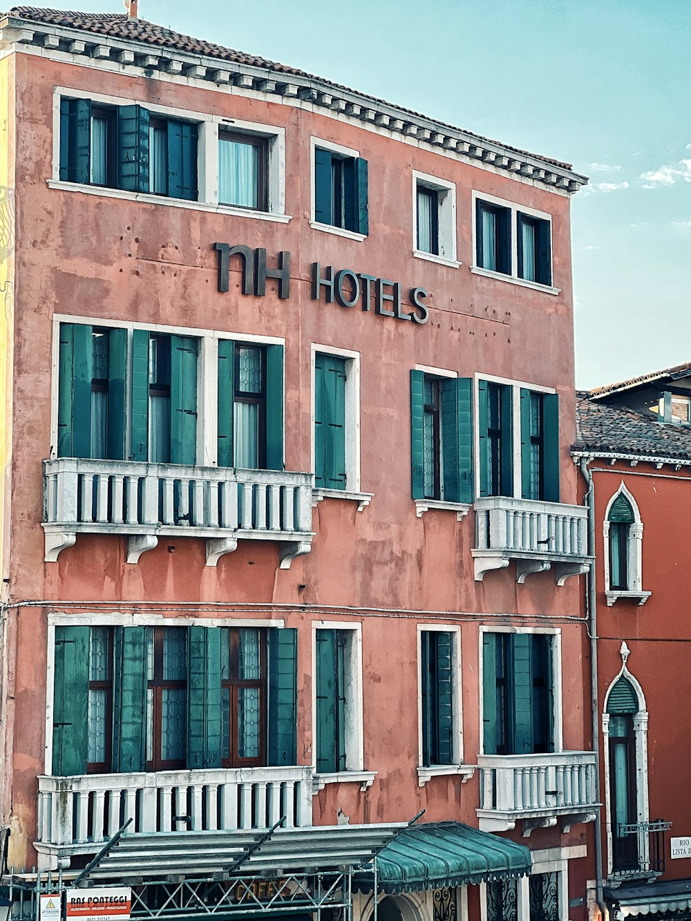 a tall pink building with balconies and windows