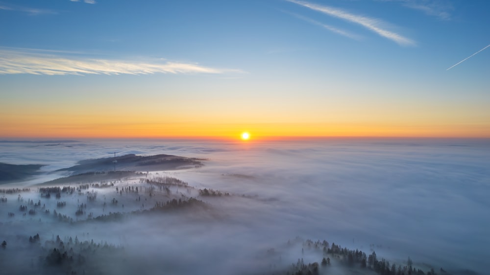 Die Sonne geht über einem nebligen Tal unter