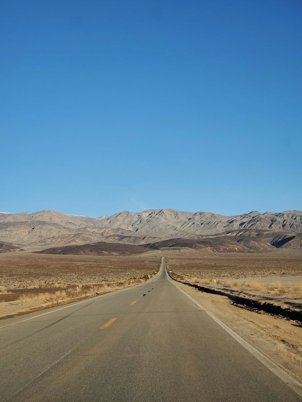 a long empty road with mountains in the background