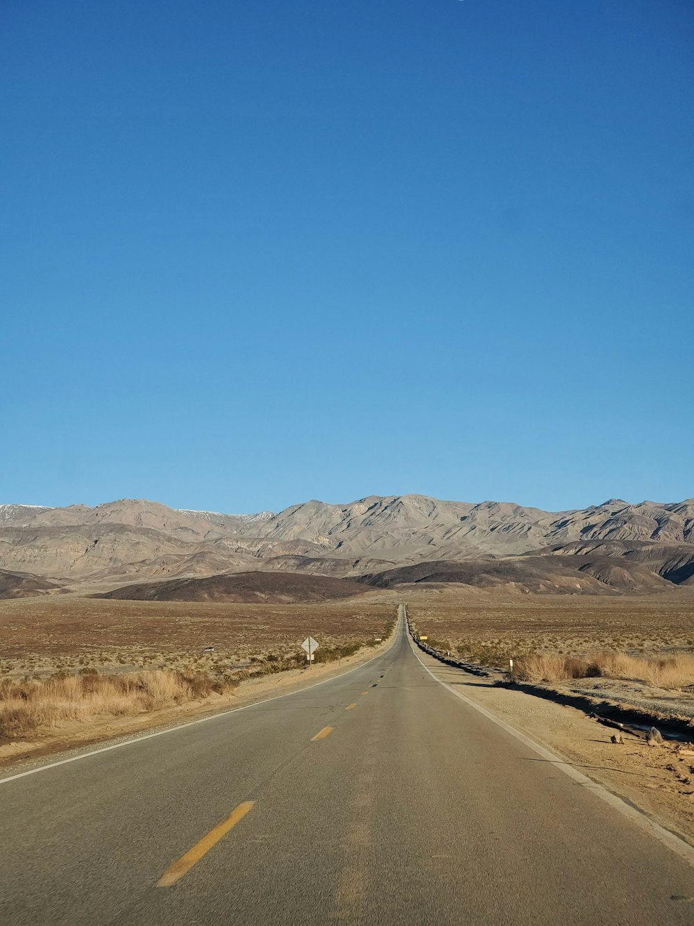 an empty road with mountains in the background