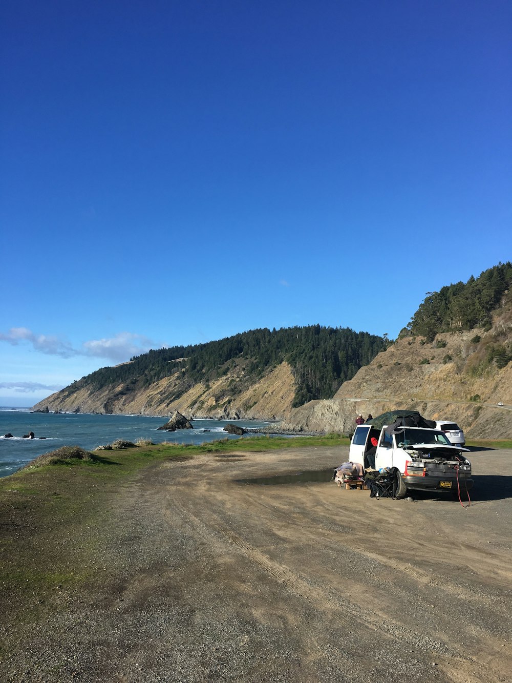 a truck parked on a dirt road next to the ocean