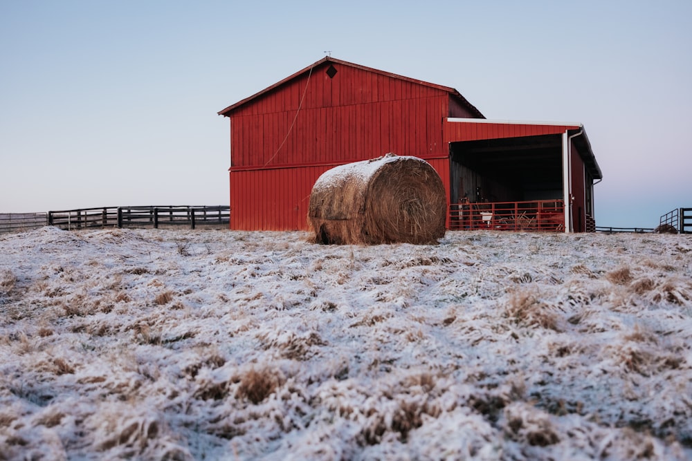 a red barn with a bale of hay in front of it