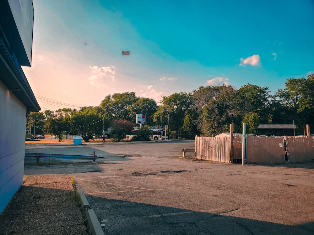 an empty parking lot with a kite flying in the sky