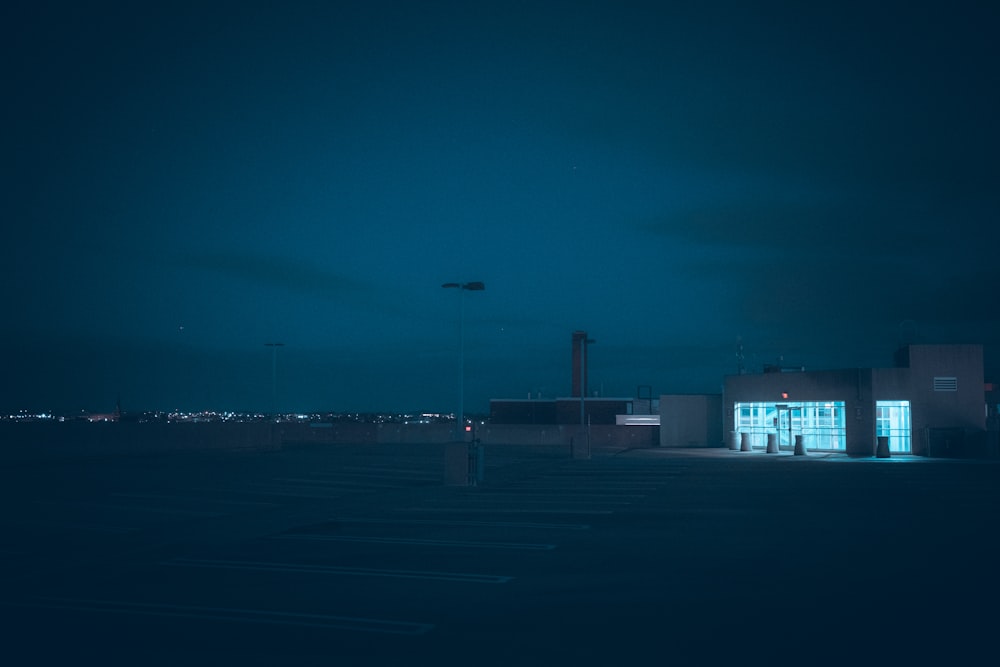 an empty parking lot at night with a building in the background