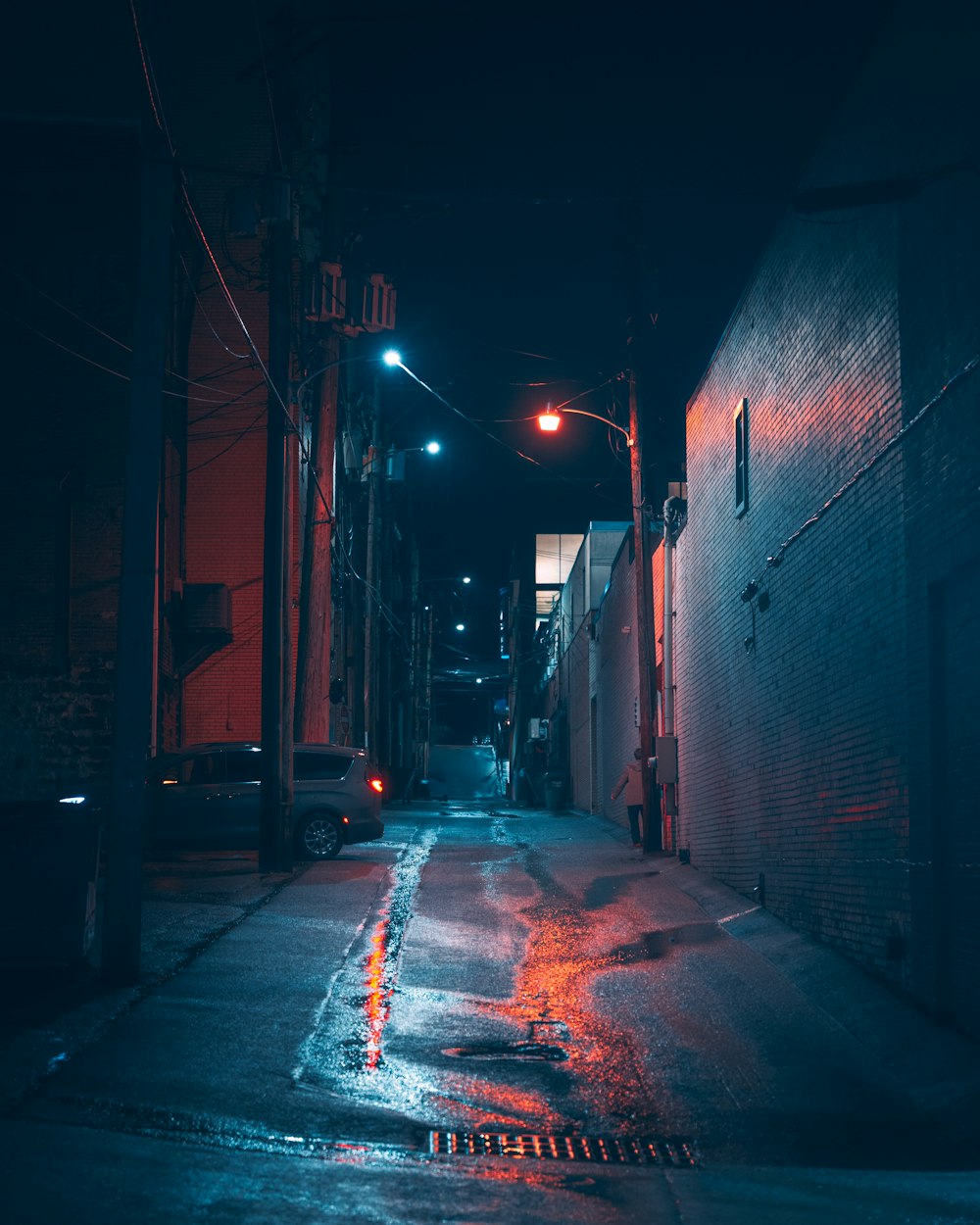 a dark alley at night with a car parked on the side of the street