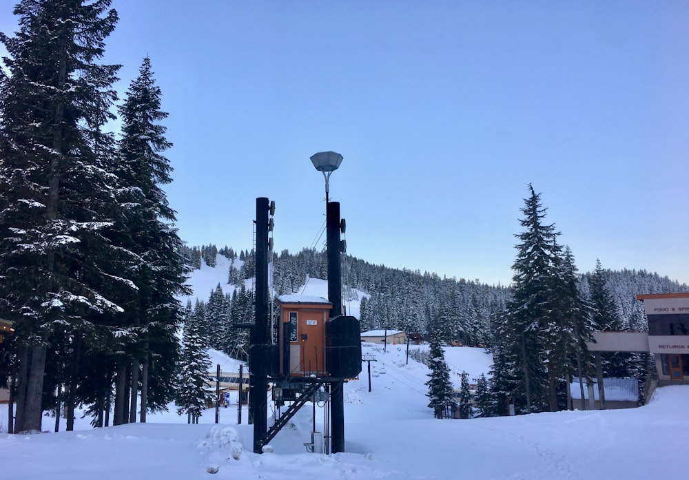 a snow covered ski slope with trees and a building in the background