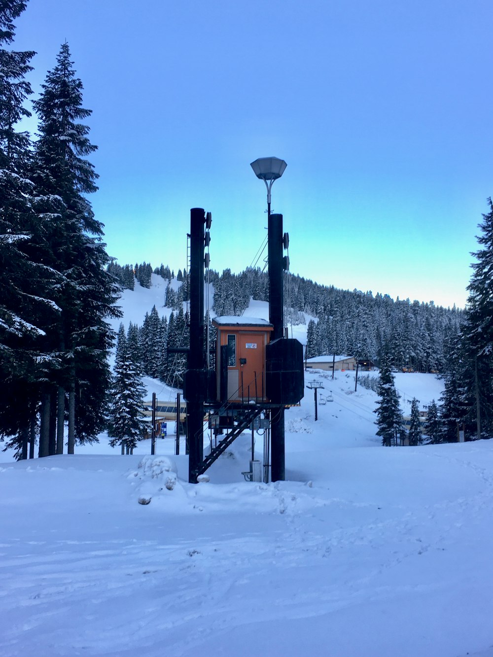 a snow covered ski slope with a ski lift in the background