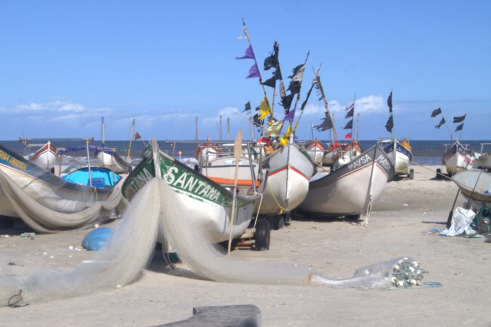eine Gruppe von Booten, die auf einem Sandstrand sitzen