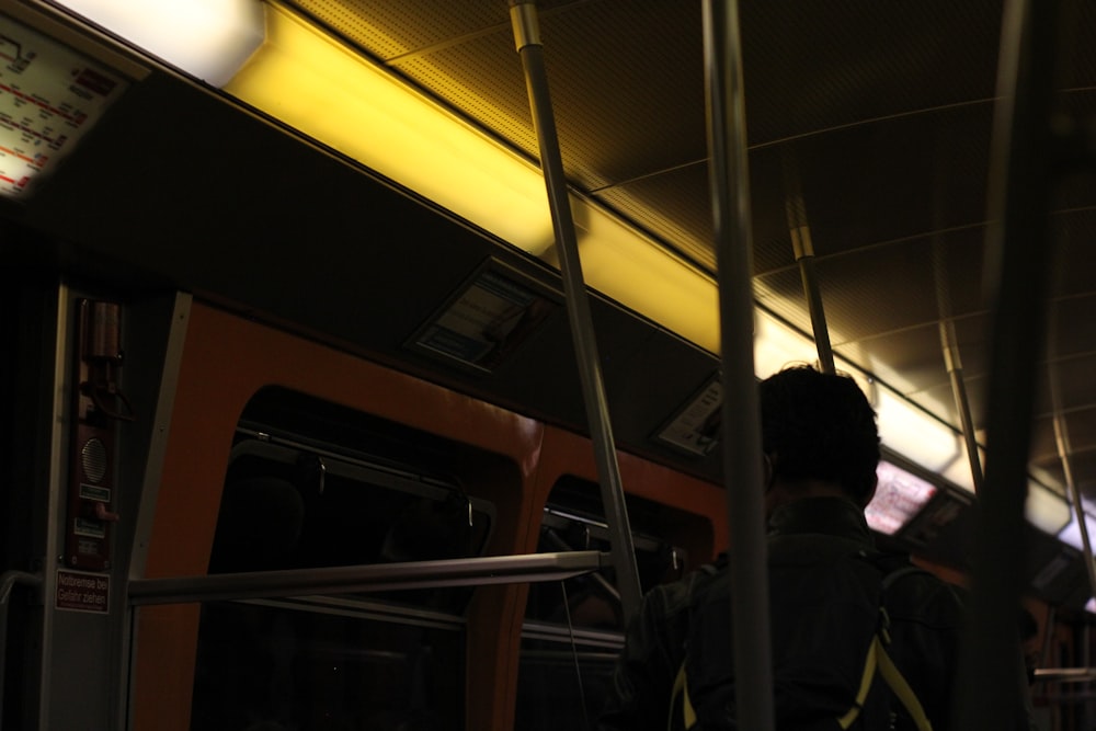 a man standing on a subway train with his back to the camera