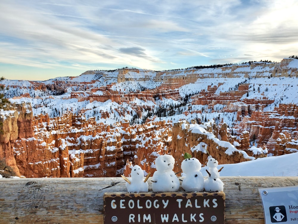 a group of snowmen sitting on top of a wooden fence