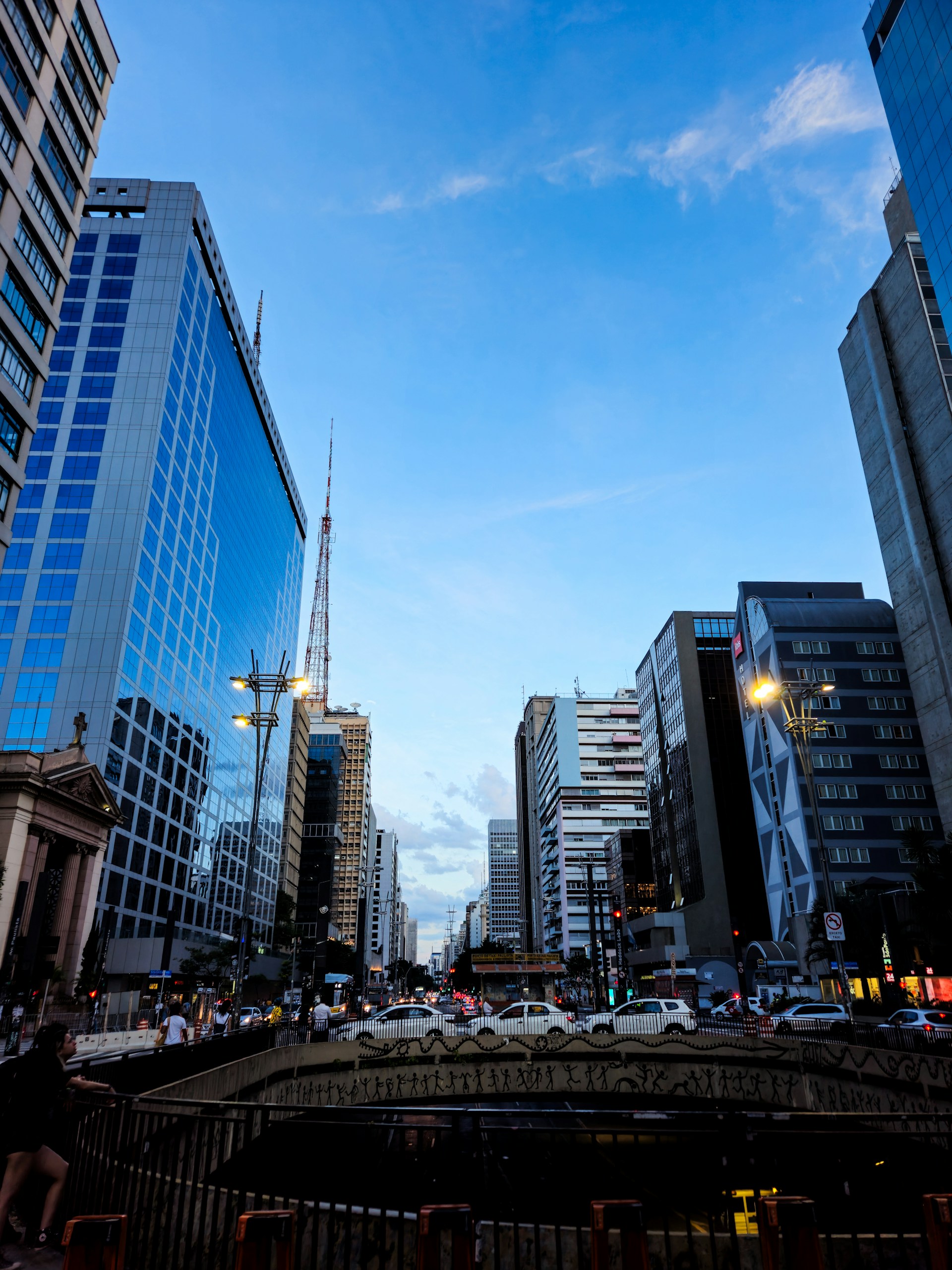 a city street with tall buildings and a bridge