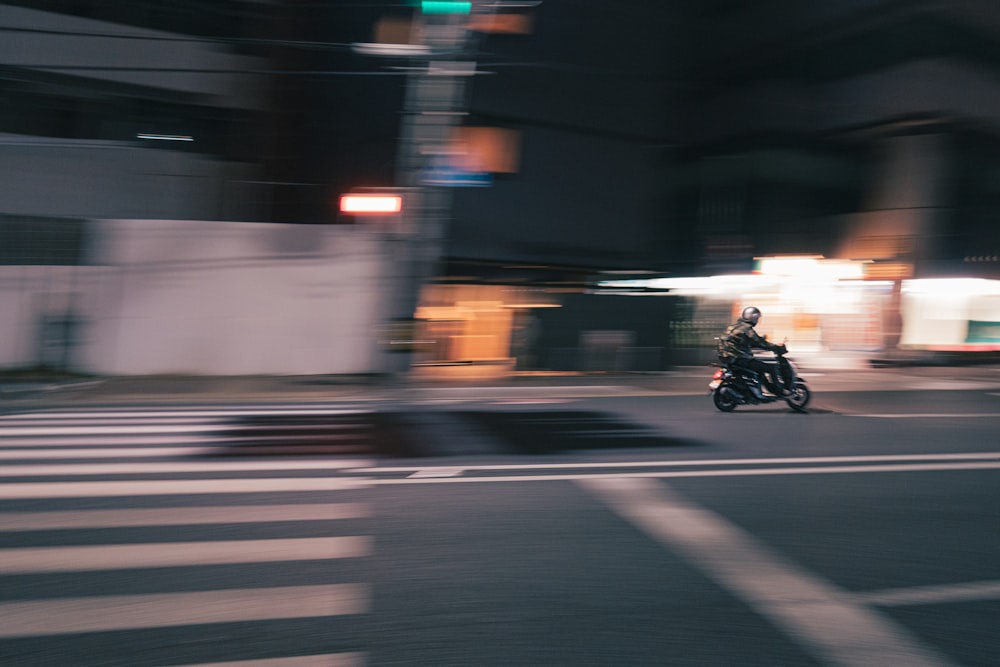 a person riding a motorcycle down a street at night