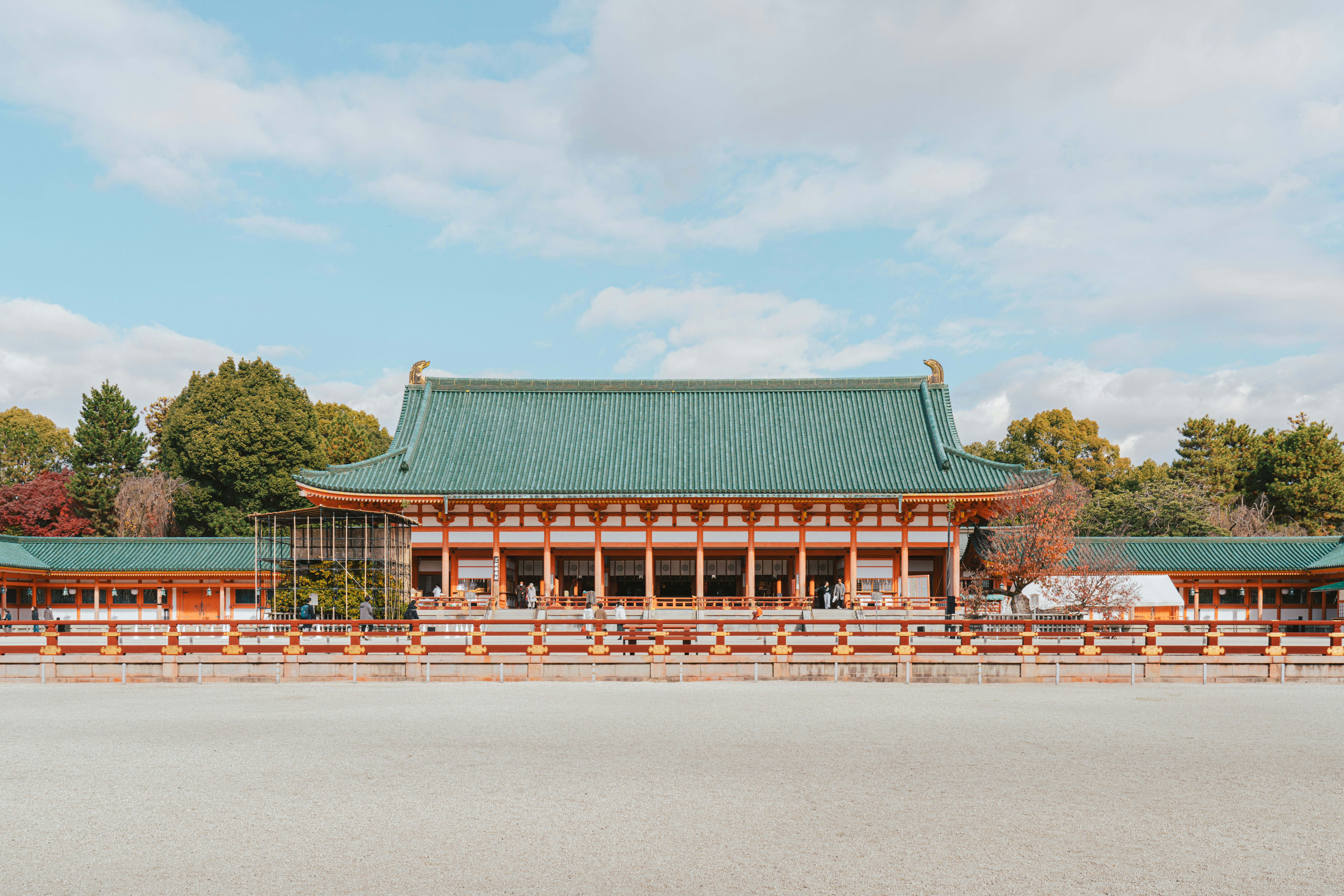 a large building with a green roof in front of trees