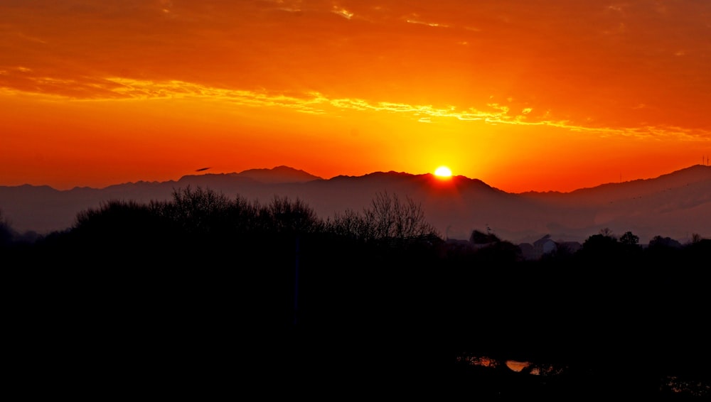 the sun is setting over a mountain range