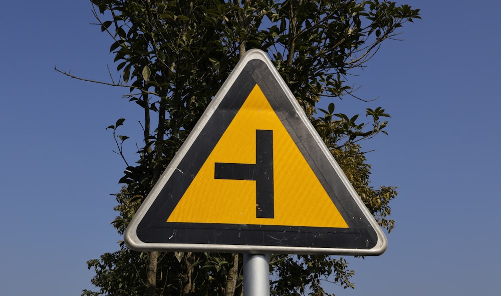 a yellow and black triangular sign with a black h on it