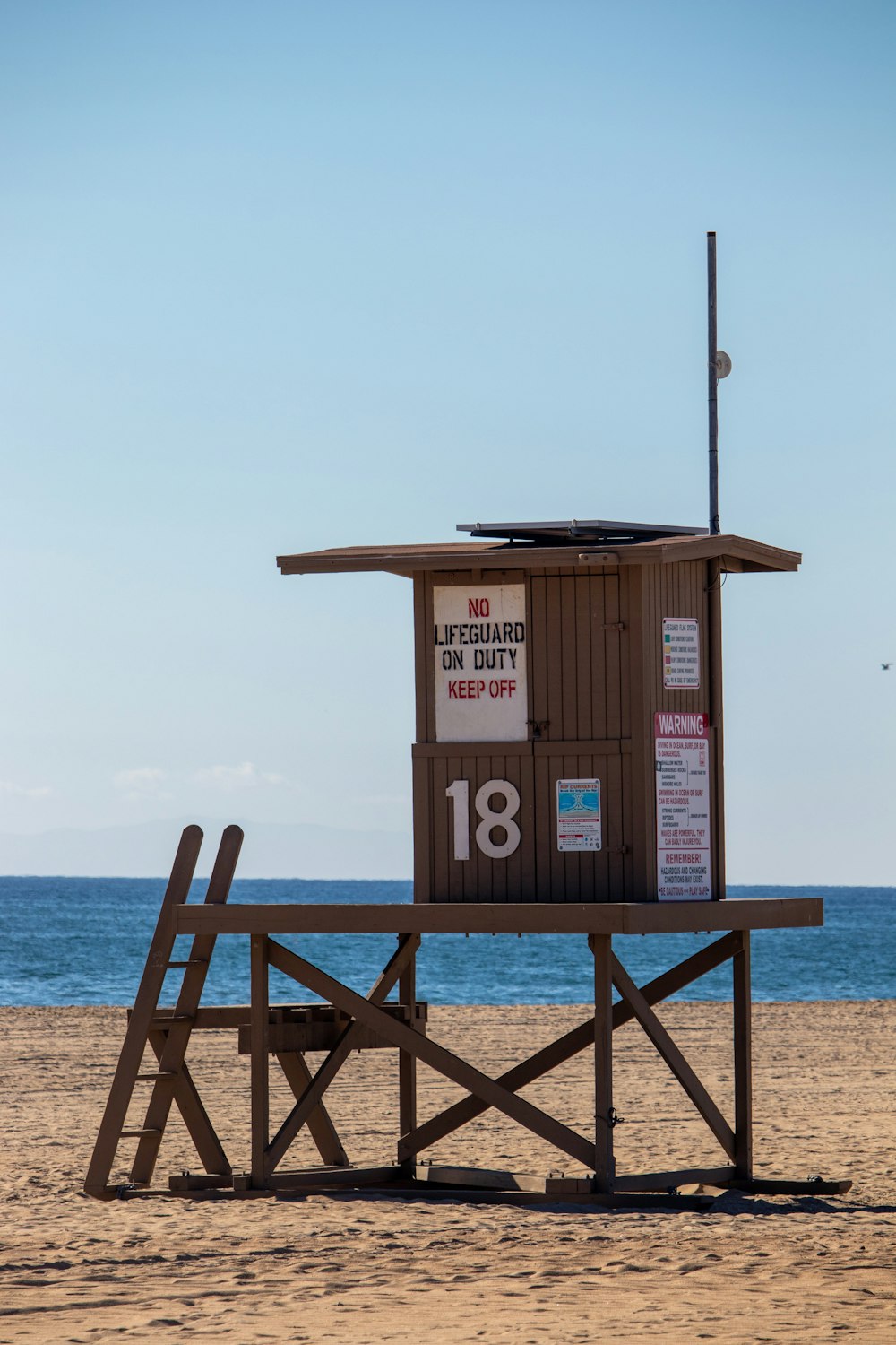 a lifeguard stand on the beach with a lifeguard flag