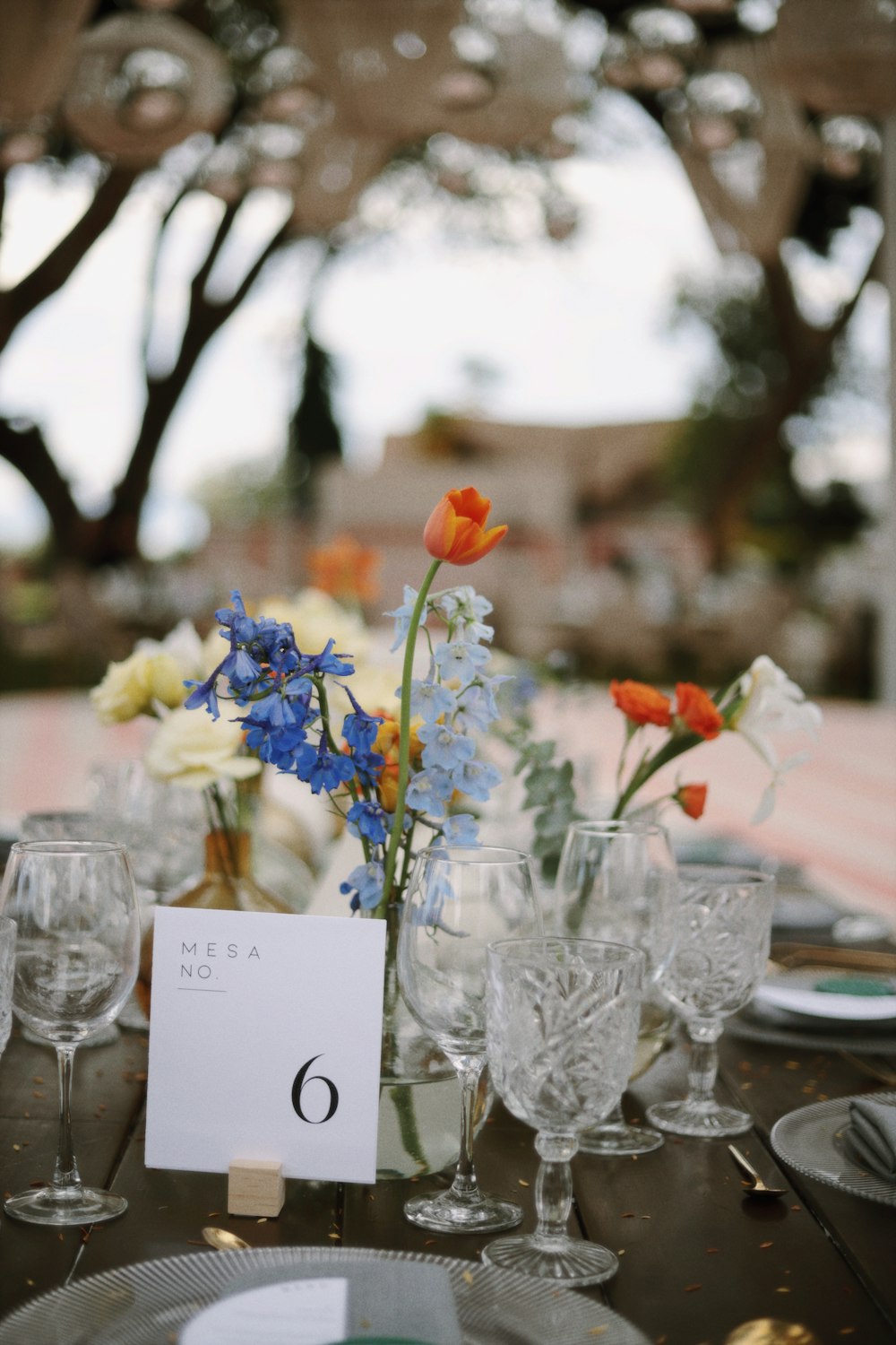 a table is set with glasses, plates, and flowers