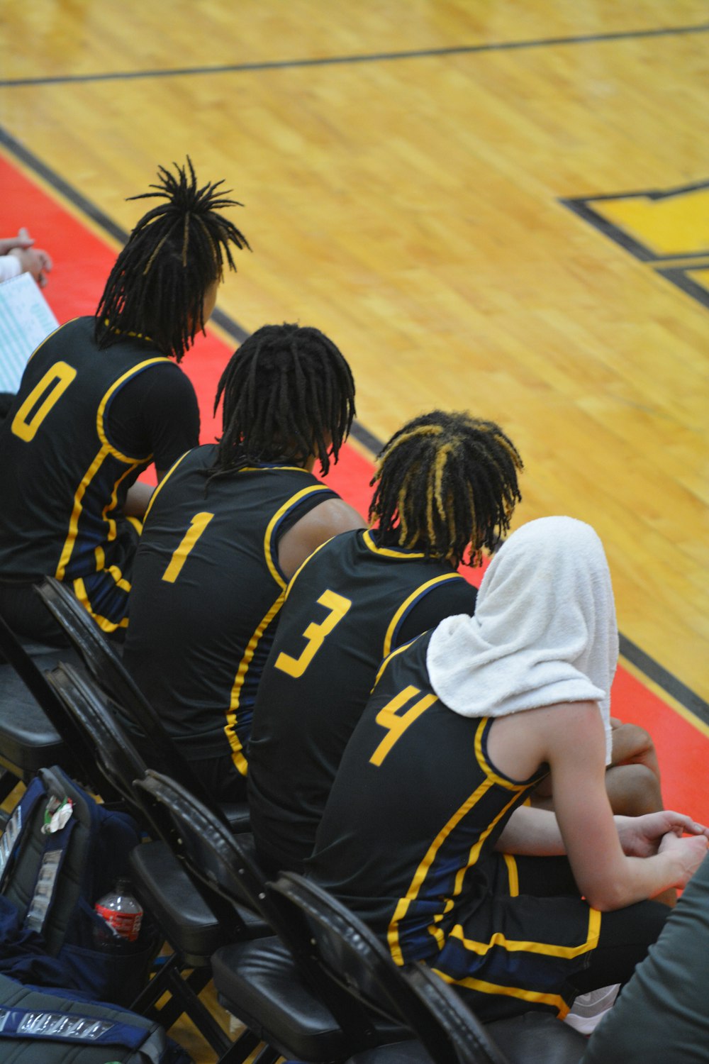 a group of young men sitting on top of a basketball court