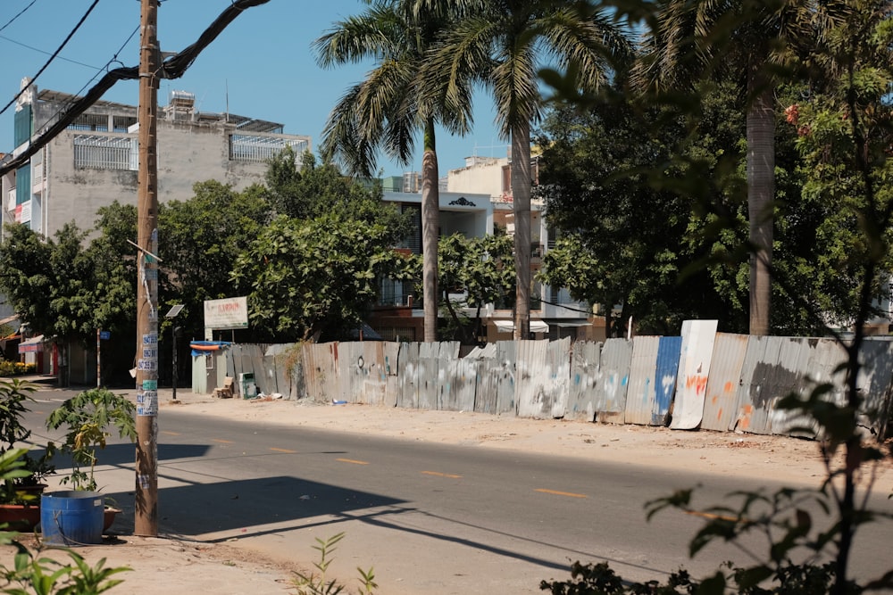 a street with a fence and palm trees