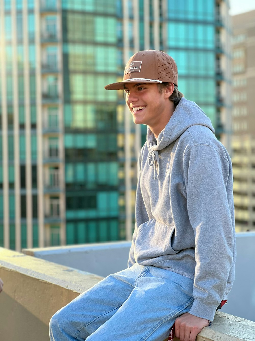 a young man sitting on a ledge in front of a tall building