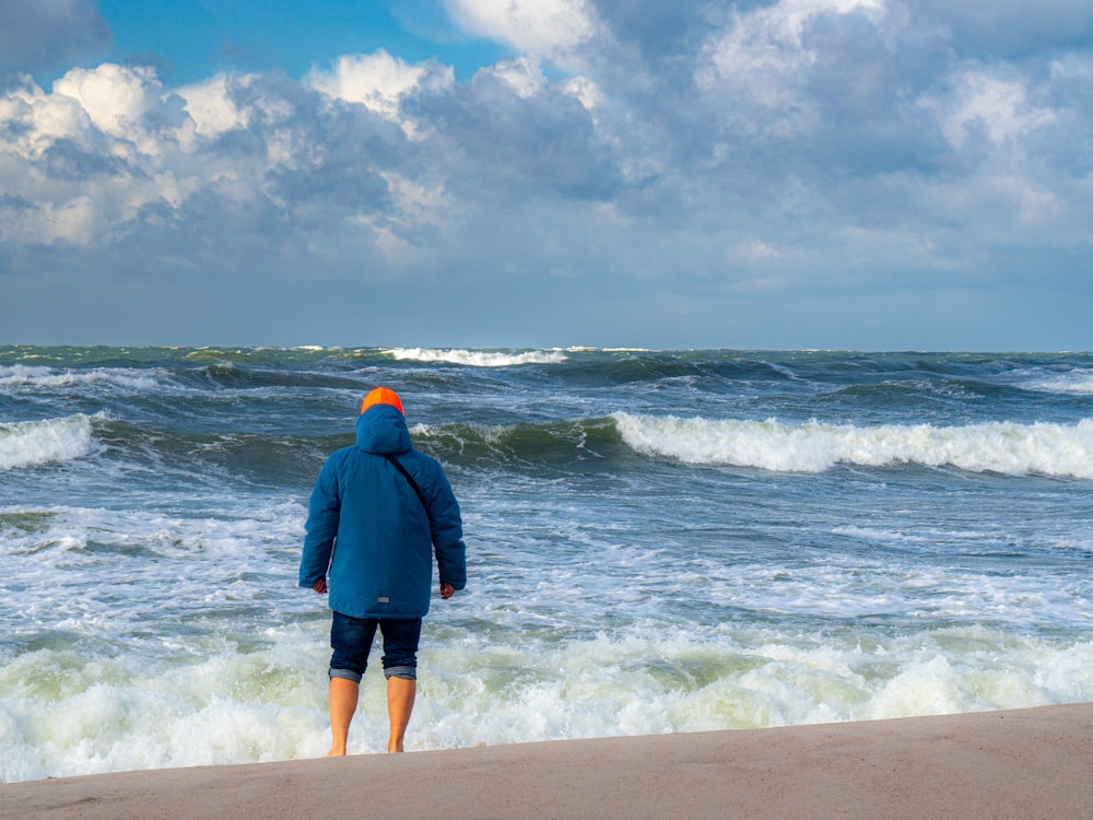 ein Mann, der an einem Strand steht und auf das Meer blickt