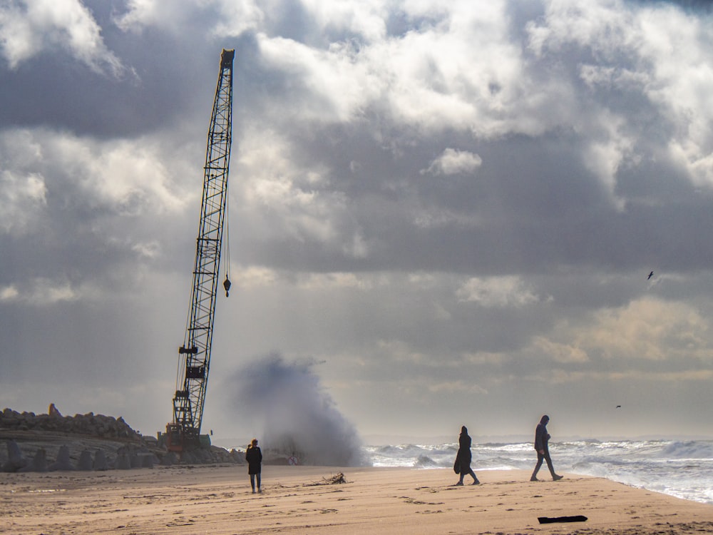 people walking on a beach near a crane