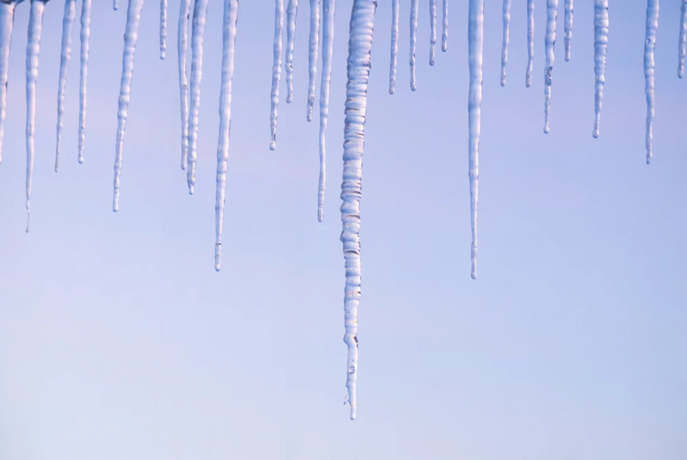 Icicles hanging from a roof edge against the winter sky