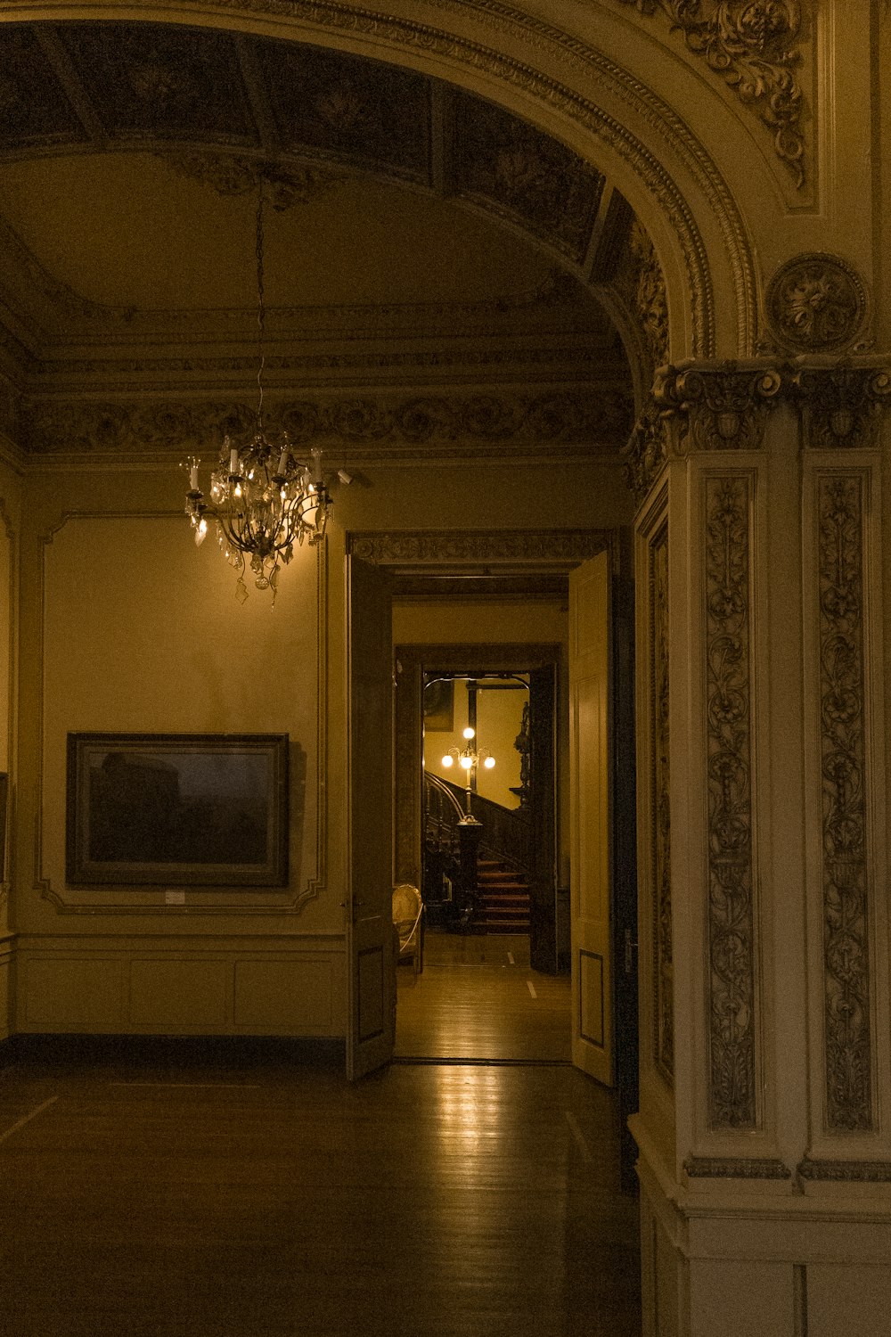 a hallway with a chandelier and a painting on the wall