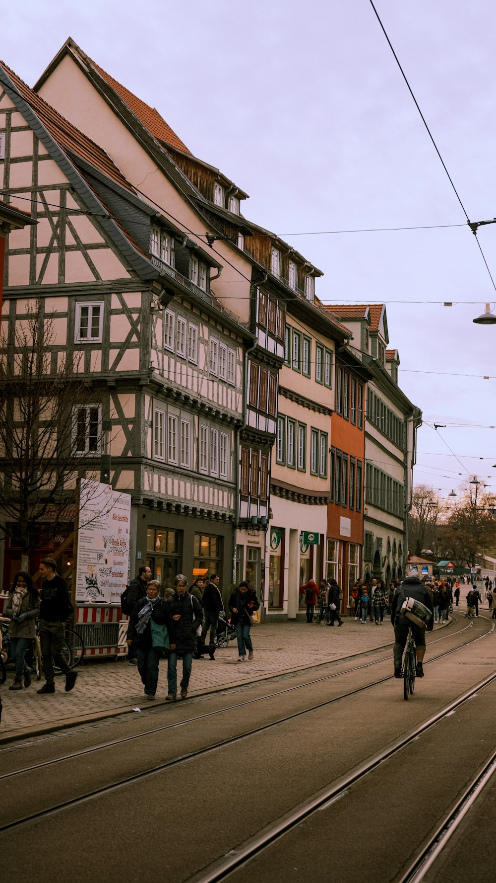 a group of people walking down a street next to tall buildings