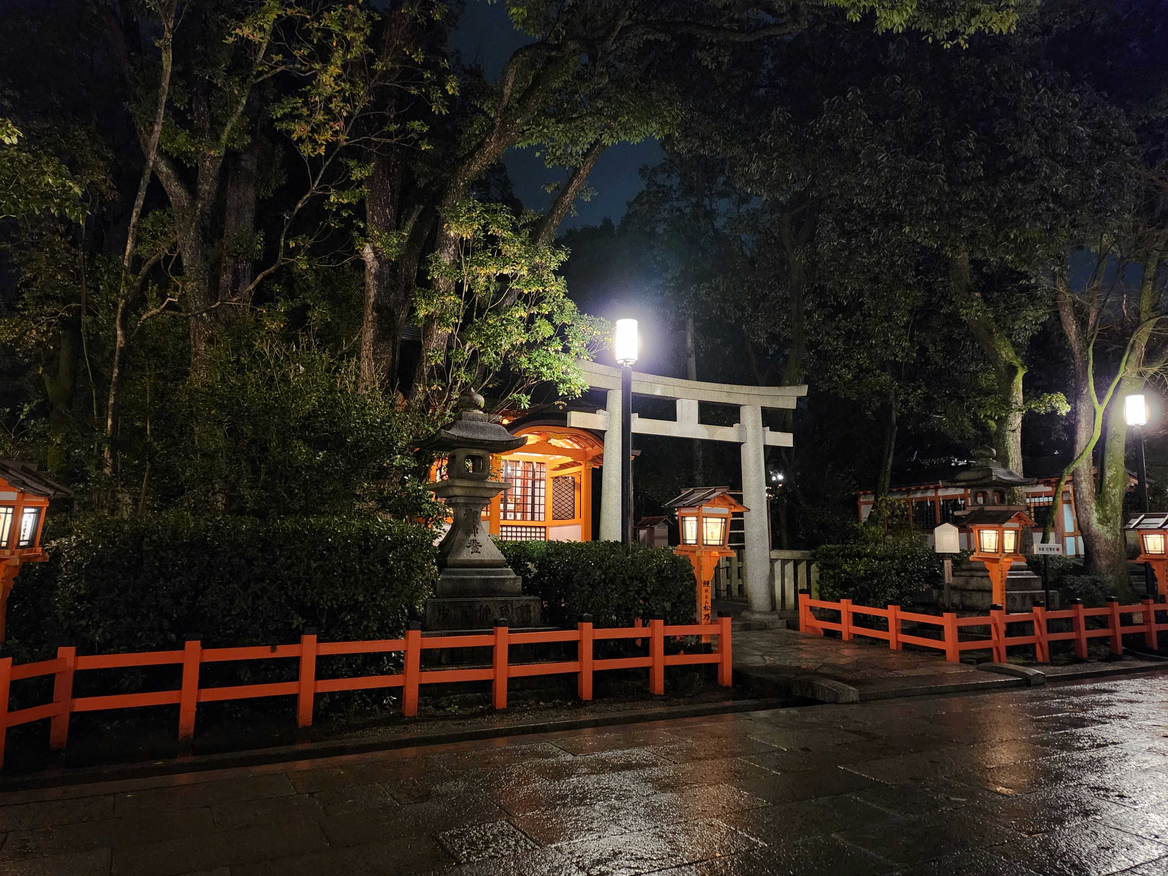 a japanese shrine lit up at night in the rain