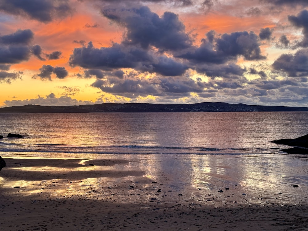 a person walking on a beach at sunset