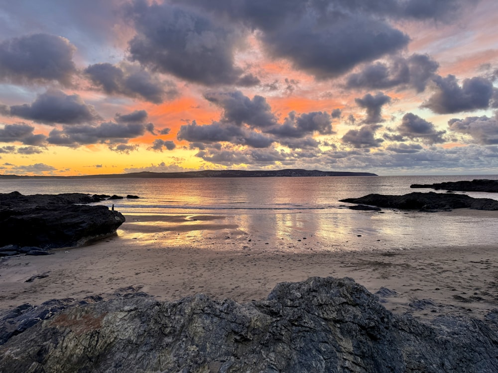 the sun is setting over the water and rocks