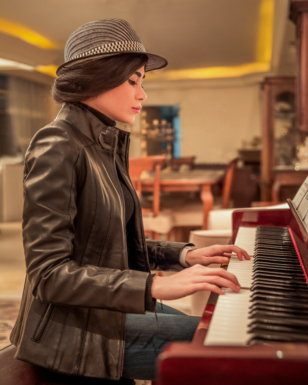 a woman sitting at a piano with a hat on