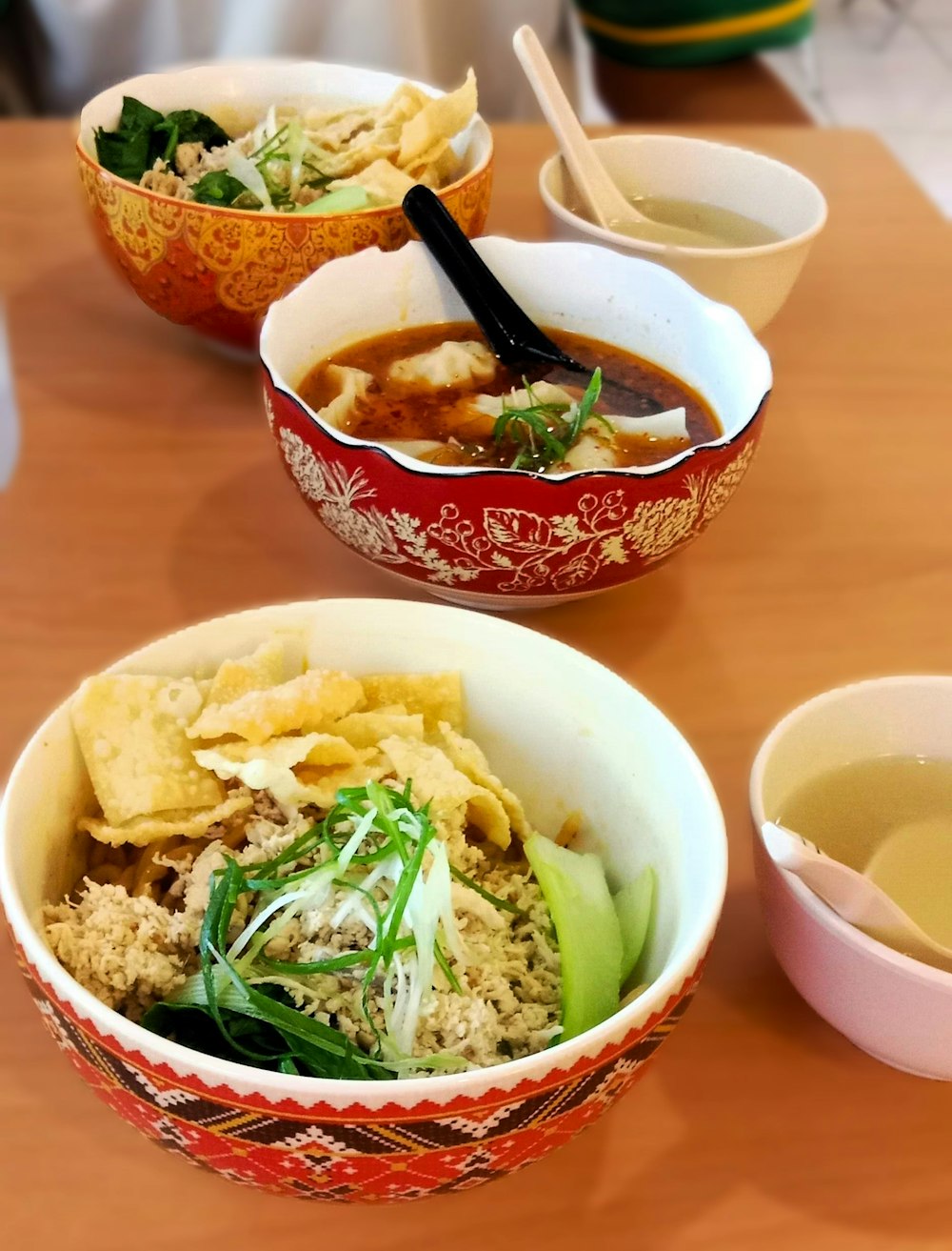 three bowls of food on a wooden table