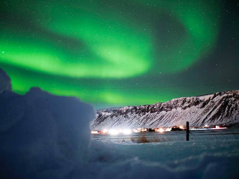 a green and white aurora over a snowy landscape