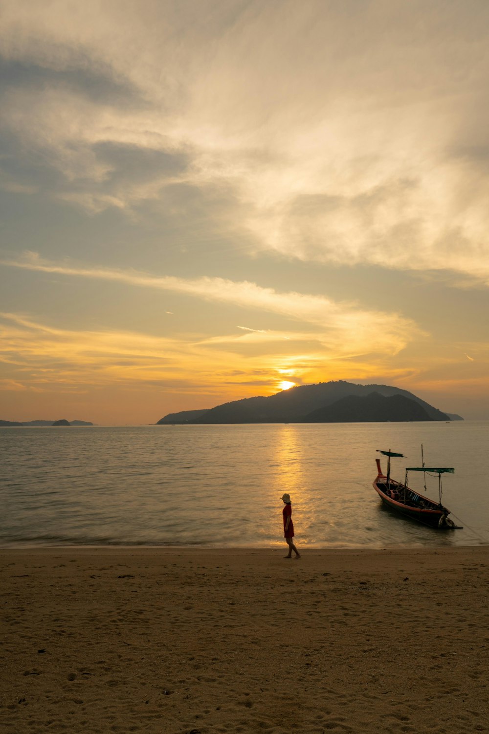 a person walking on a beach next to a boat