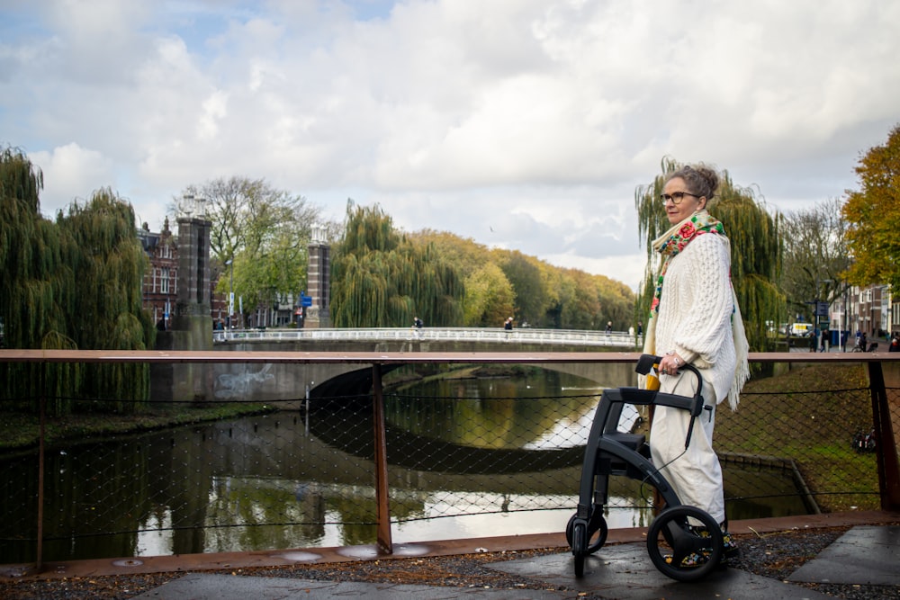 a woman standing next to a bike near a river