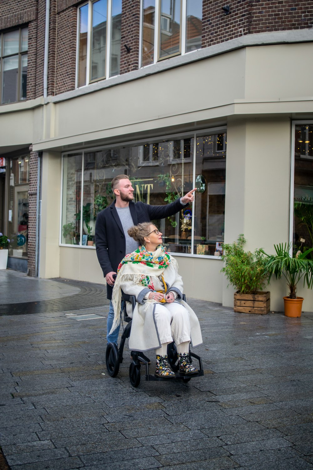 a man standing next to a woman in a wheel chair
