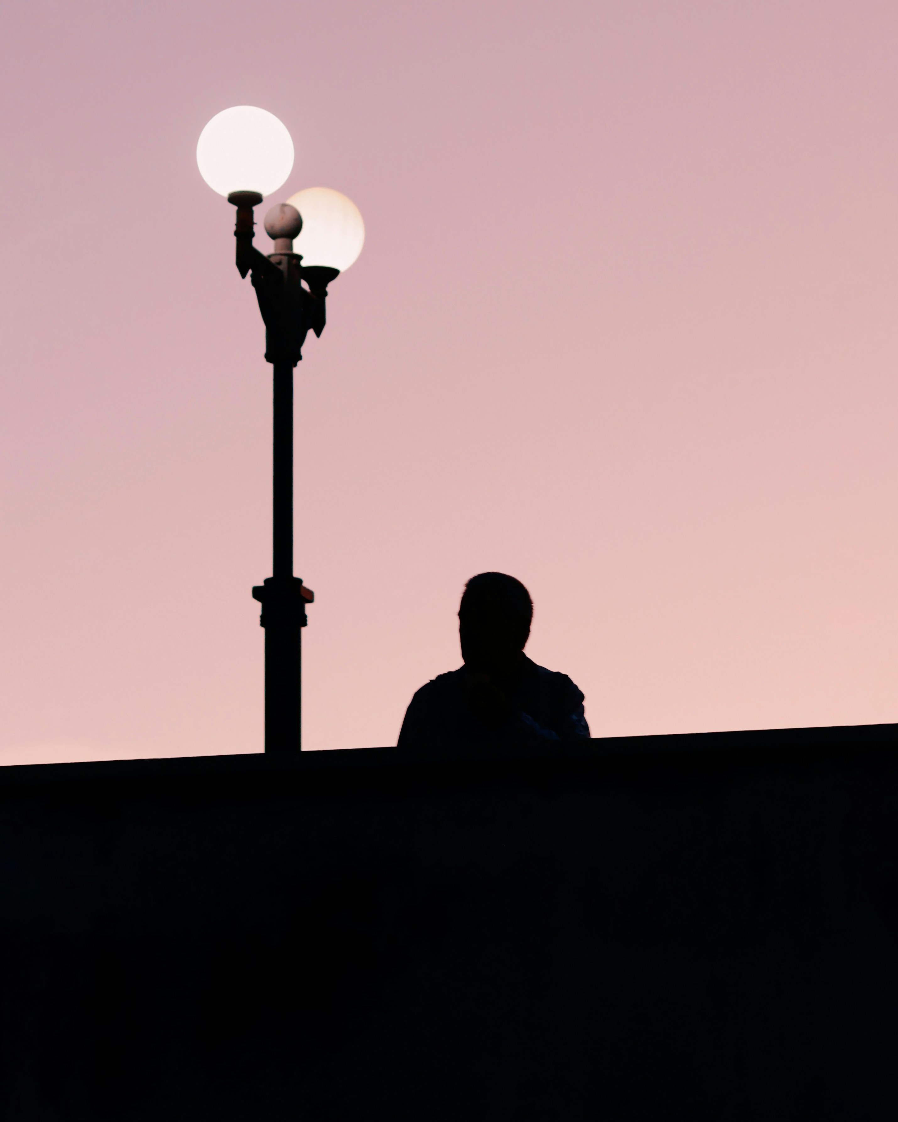 a man sitting on a ledge next to a street light