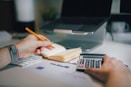 a person sitting at a desk with a calculator and a notebook