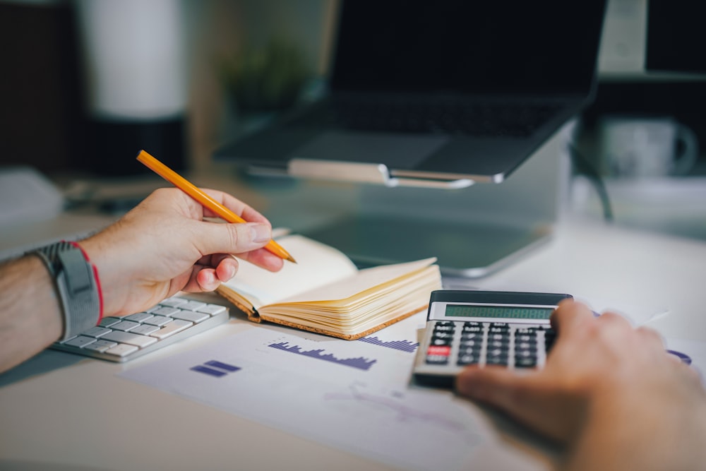 a person sitting at a desk with a calculator and a notebook