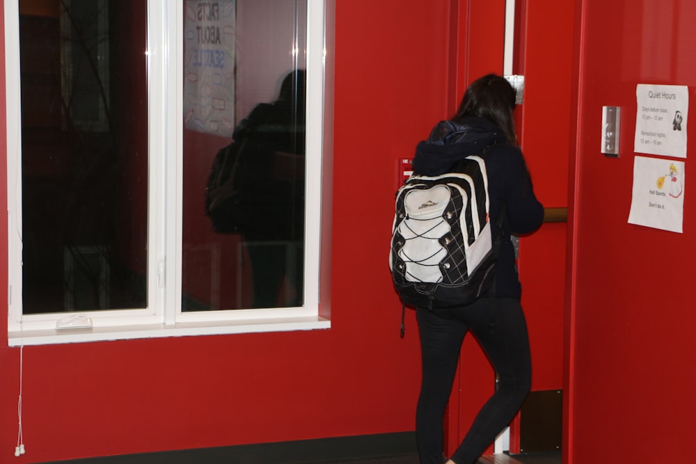 a woman with a backpack is entering a building