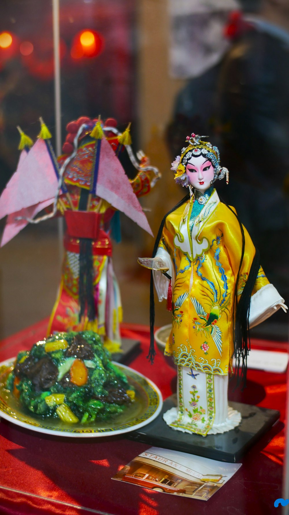 una statua di una donna in kimono accanto a un piatto di cibo