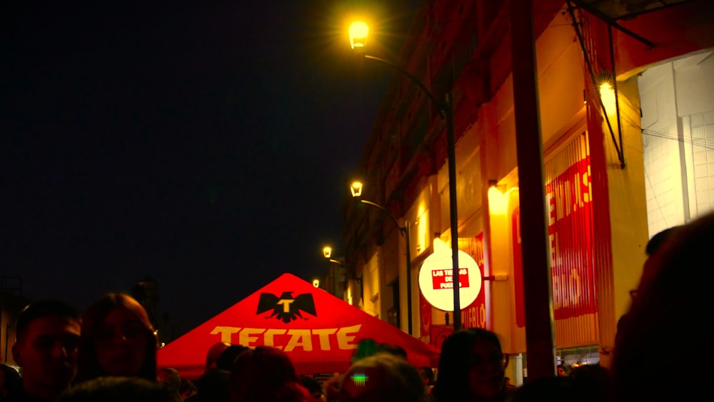 a crowd of people standing around a red tent