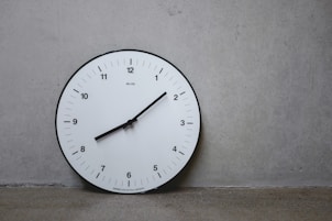 a white clock on a wall with a black second hand