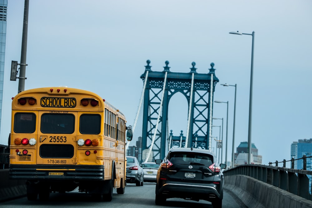 a yellow school bus driving down a street next to a bridge