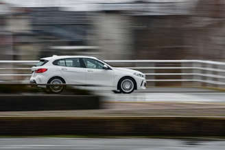 a white car driving down a wet road