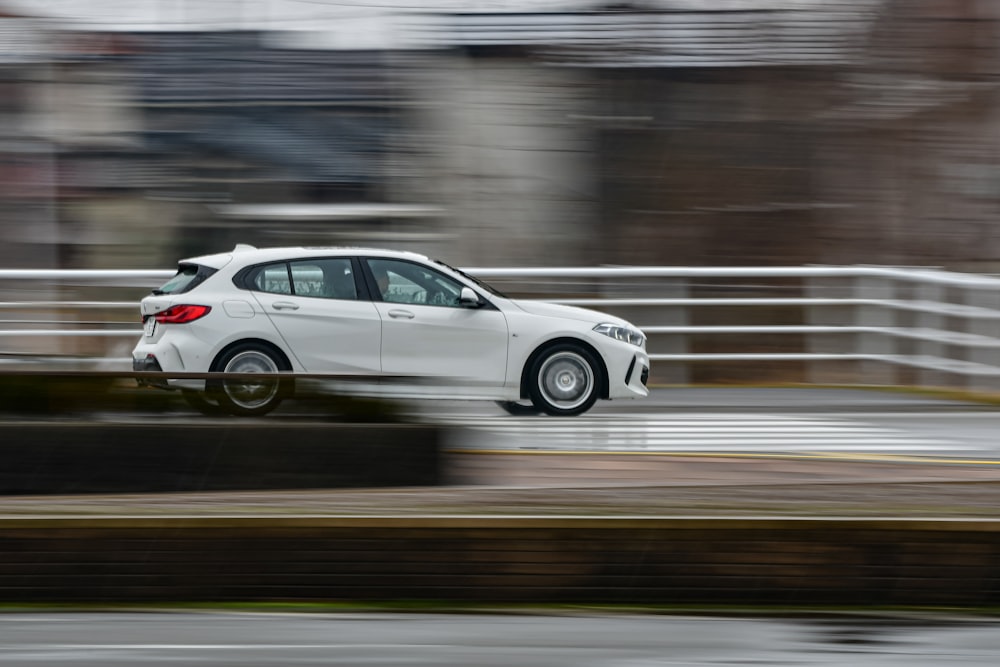 a white car driving down a wet road