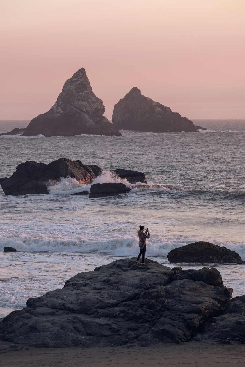 a man standing on top of a rock near the ocean