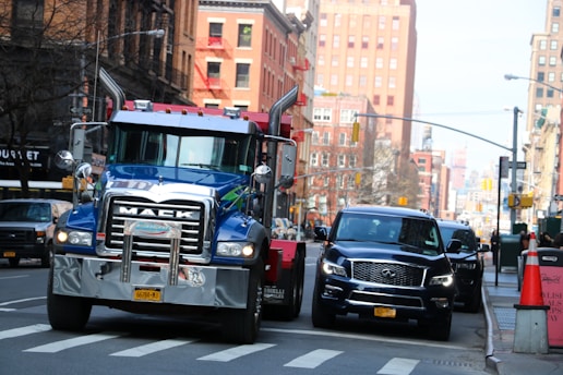 a truck driving down a street next to a car